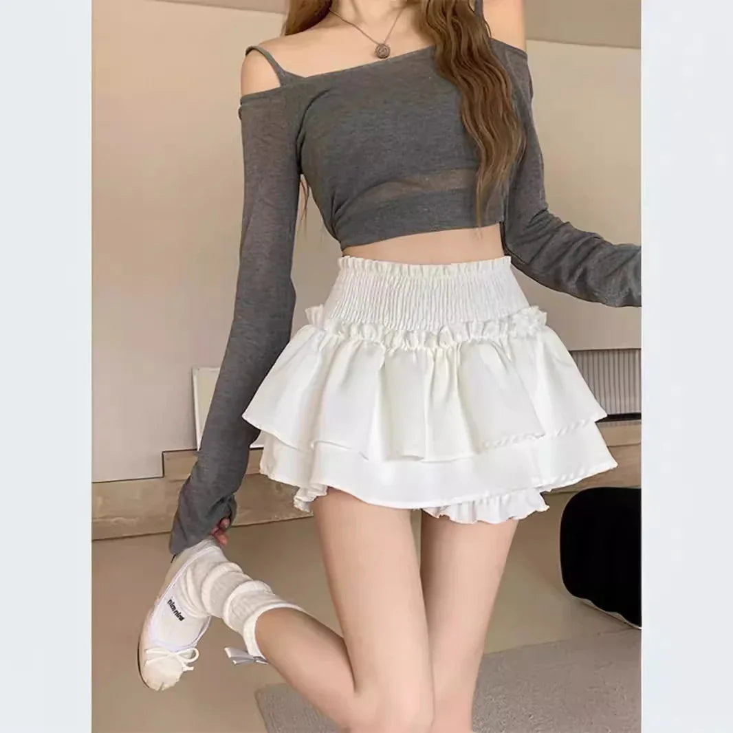 Woman wearing gray off-shoulder crop top with long sleeves and white layered ruffle mini skirt
