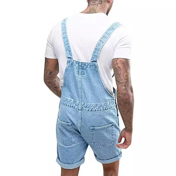 Man wearing light blue denim short overalls with rolled cuffs and white t-shirt, tattoos on arms