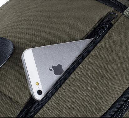 Silver iPhone partially inside black zipper pocket of an olive green canvas bag