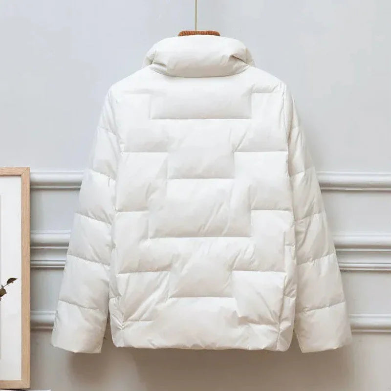 Back view of a white quilted puffer jacket with high collar hanging indoors