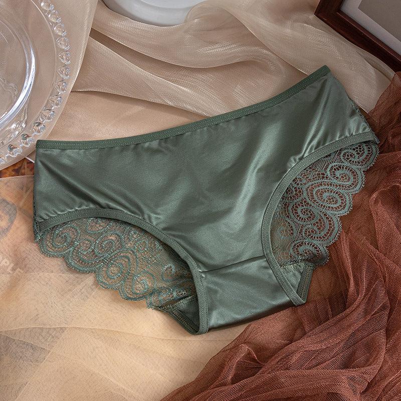 Green satin women’s panties with decorative lace trim on beige and brown fabric backdrop