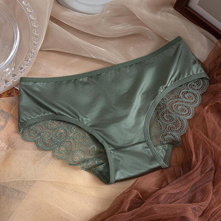 Green satin women’s panties with decorative lace trim on beige and brown fabric backdrop
