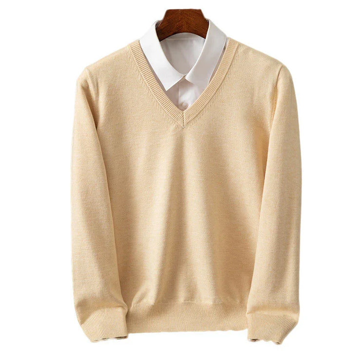 Beige V-neck sweater layered over white collared shirt on wooden hanger