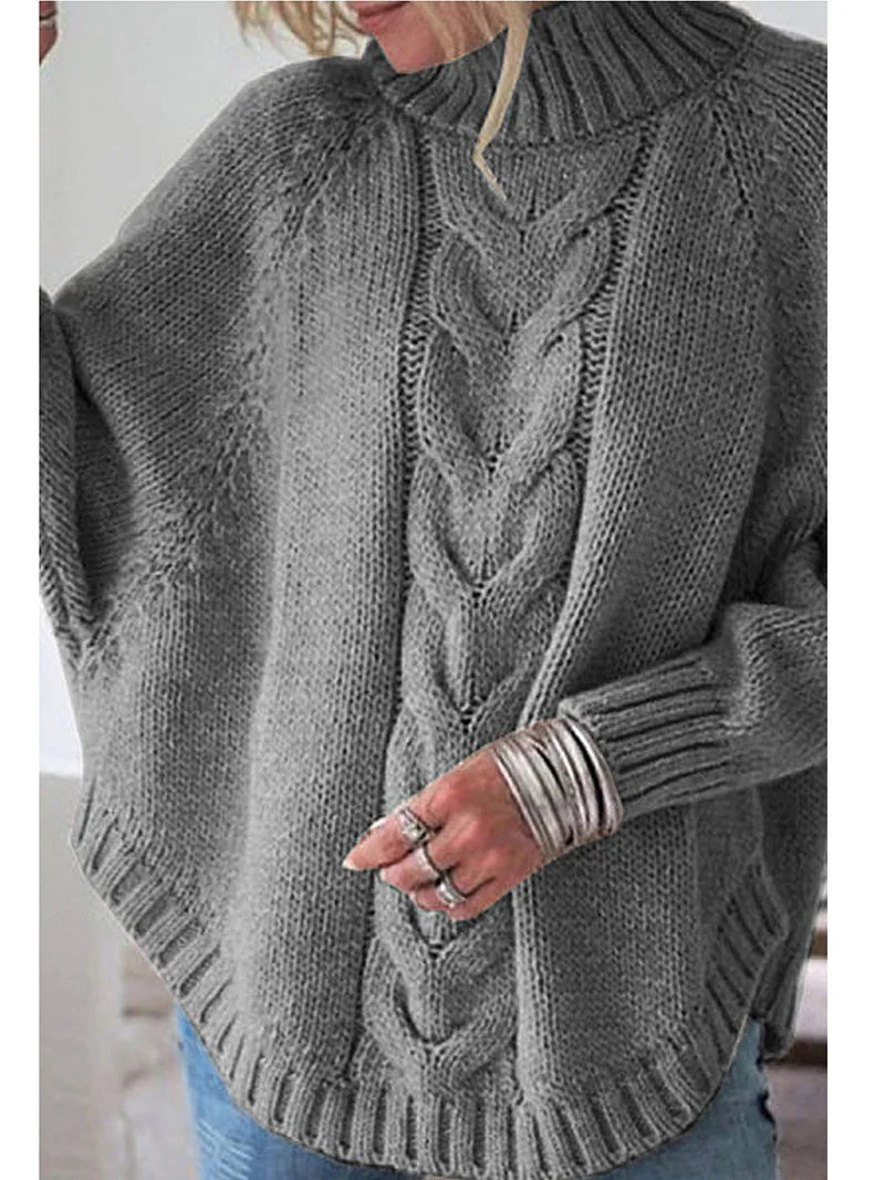 Woman wearing gray chunky knit sweater with central cable knit pattern and ribbed high neck