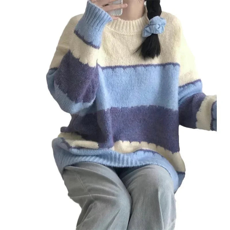 Person wearing a cozy oversized knit sweater with cream, light blue, and dark blue horizontal stripes