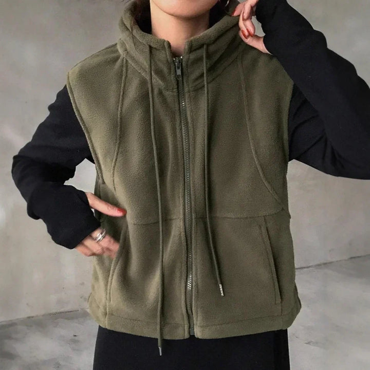 person wearing olive green fleece zip-up vest with high collar and drawstrings over black long-sleeve top