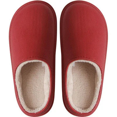 Pair of red indoor slippers with soft beige fleece lining, top view on white background