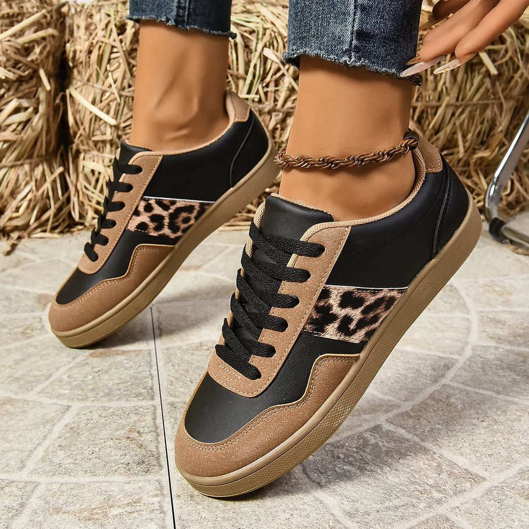 Black and brown sneakers with leopard print detail worn with ankle bracelet and rolled jeans on tiled floor
