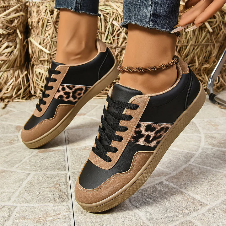 Black and brown sneakers with leopard print detail worn with ankle bracelet and rolled jeans on tiled floor