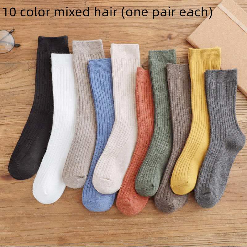 10 pairs of ribbed cotton socks in assorted colors laid out on a wooden surface