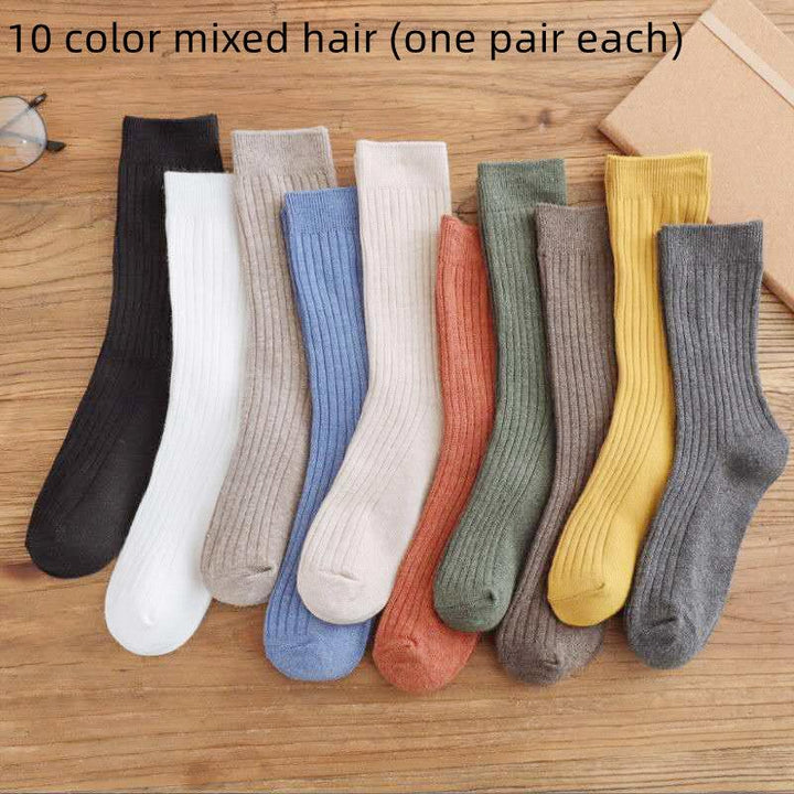 10 pairs of ribbed cotton socks in assorted colors laid out on a wooden surface