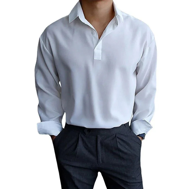 Man wearing white long-sleeve shirt with collar and black pants, hands in pockets