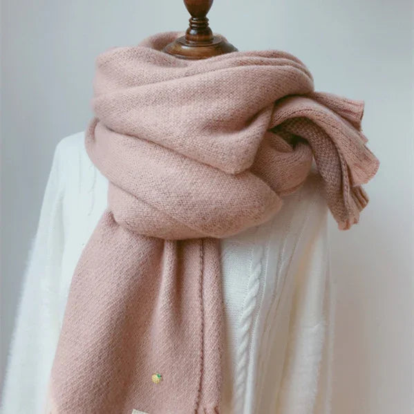 Cozy soft pink wool scarf wrapped around mannequin neck over white knit sweater