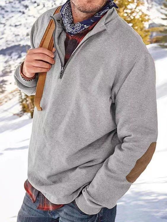 Man wearing grey quarter-zip pullover with elbow patches and bandana scarf in snowy outdoor setting