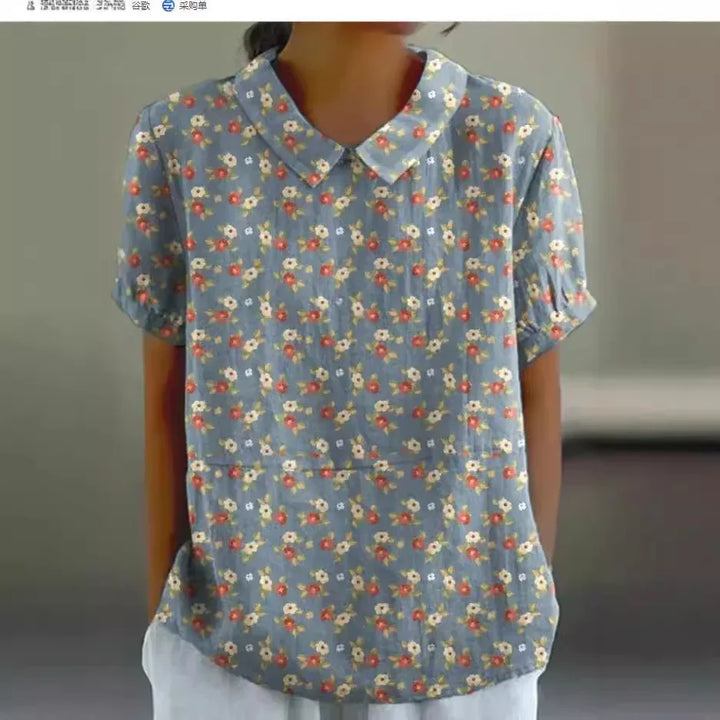 Woman wearing blue floral short-sleeve blouse with Peter Pan collar and white pants