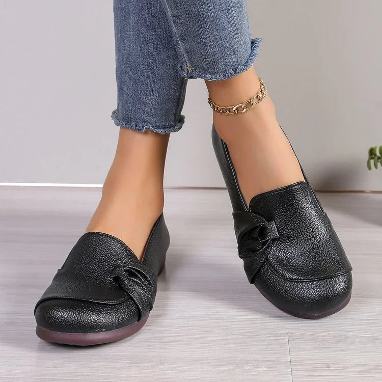 woman wearing black leather slip-on loafers with knotted detail and cropped blue jeans with raw hem