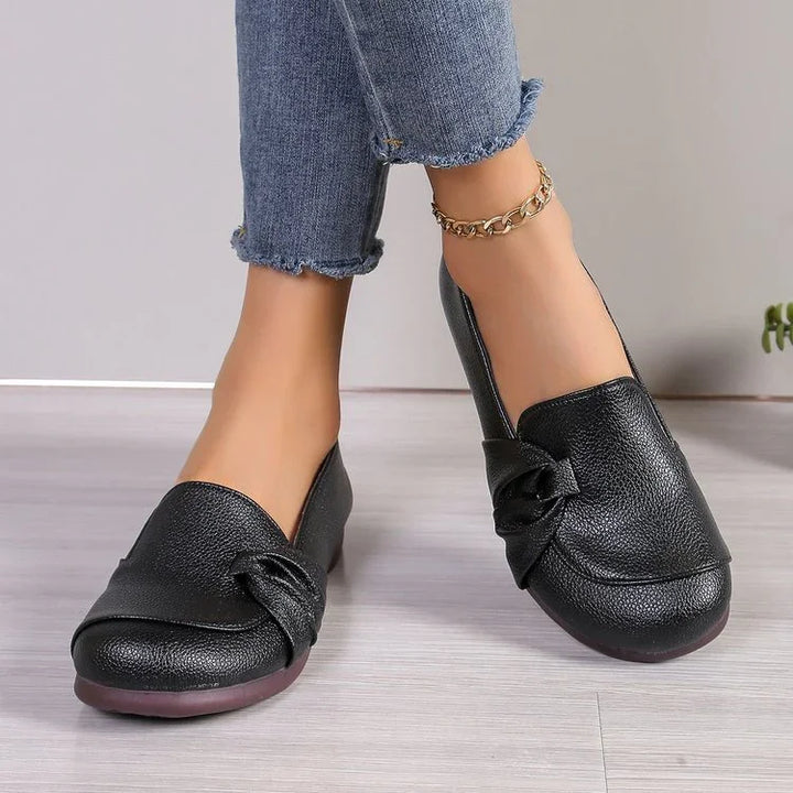woman wearing black leather slip-on loafers with knotted detail and cropped blue jeans with raw hem