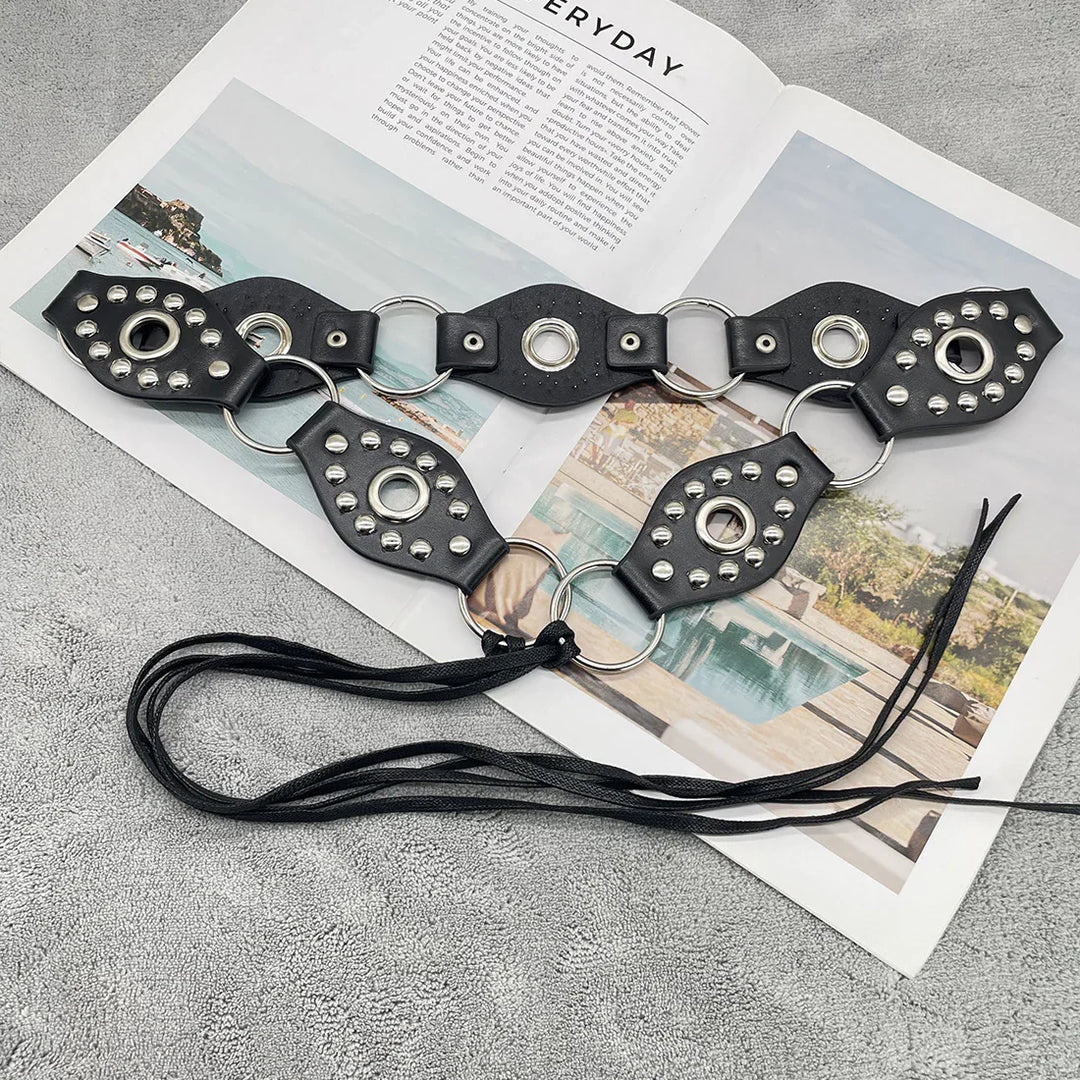 Black studded leather belt with metal rings and tassels on open lifestyle magazine