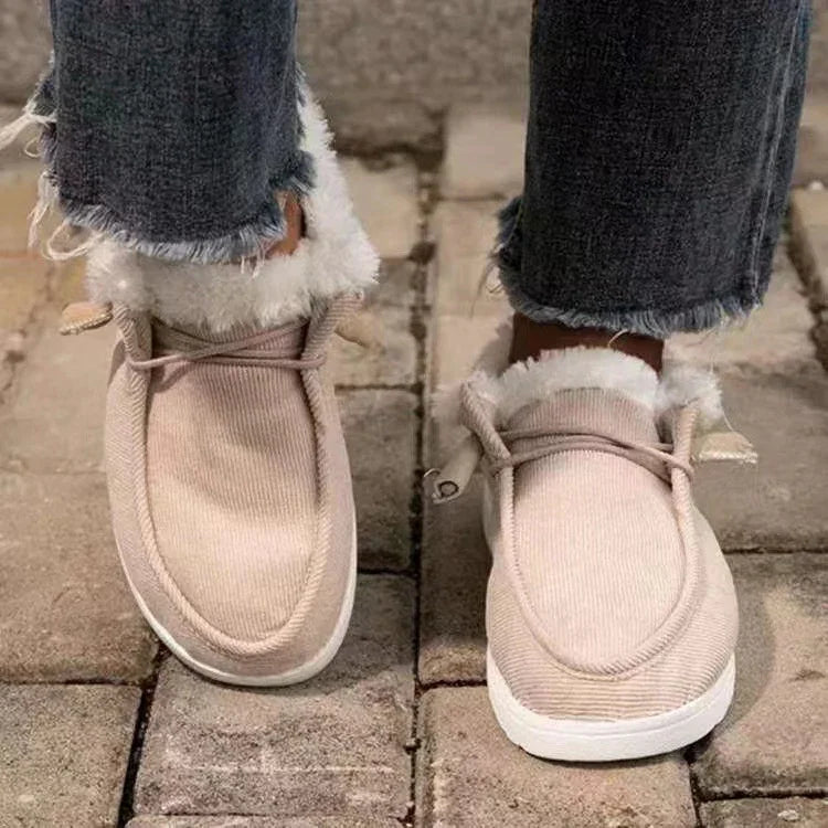 Beige faux fur-lined slip-on winter shoes worn with frayed hem jeans on stone pavement