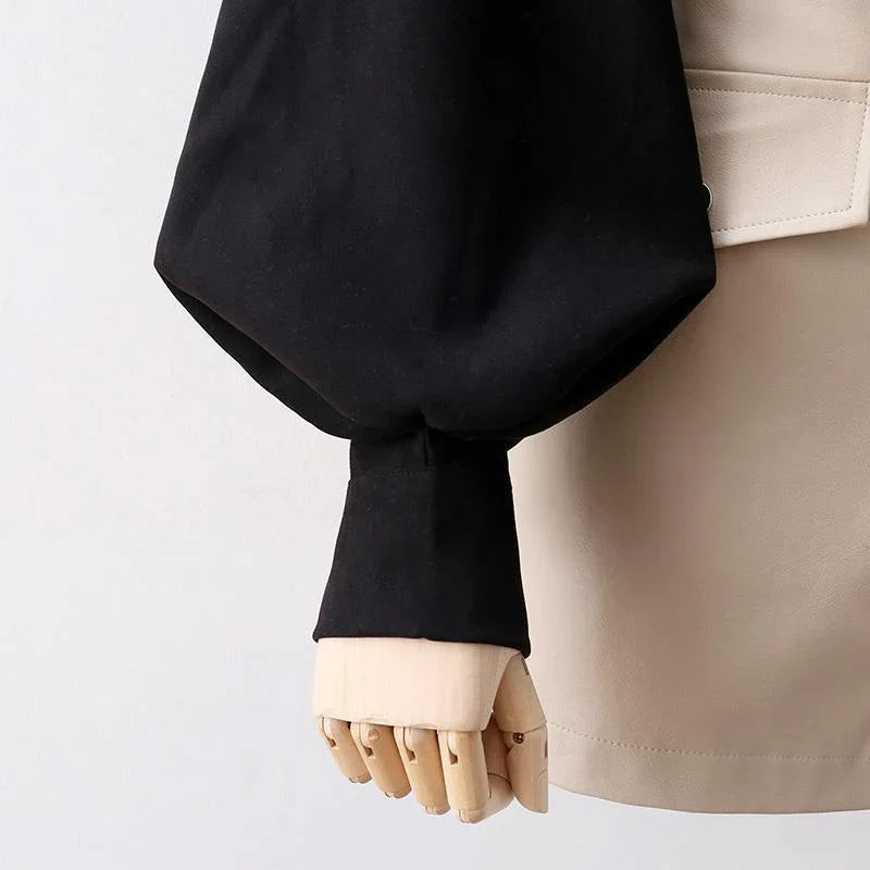 Close-up of black puff sleeve cuff on beige garment with wooden mannequin hand