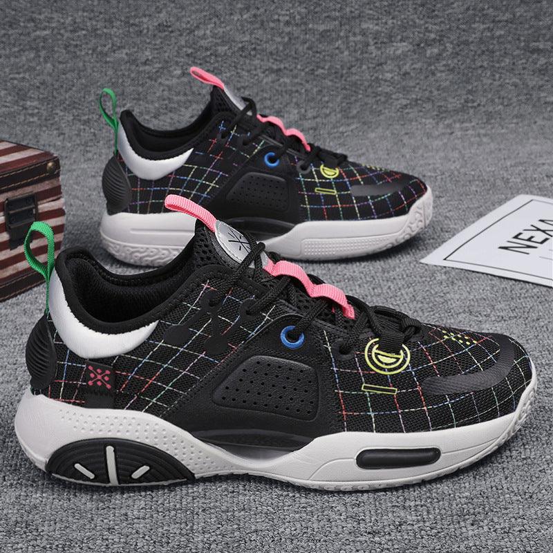 Black athletic sneakers with multicolor grid pattern, white soles, pink and green accents on gray carpet