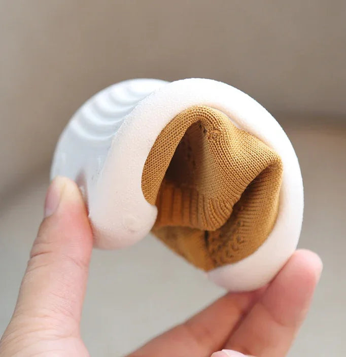 Hand holding a flexible white shoe sole with a brown knitted fabric interior, highlighting bendable design