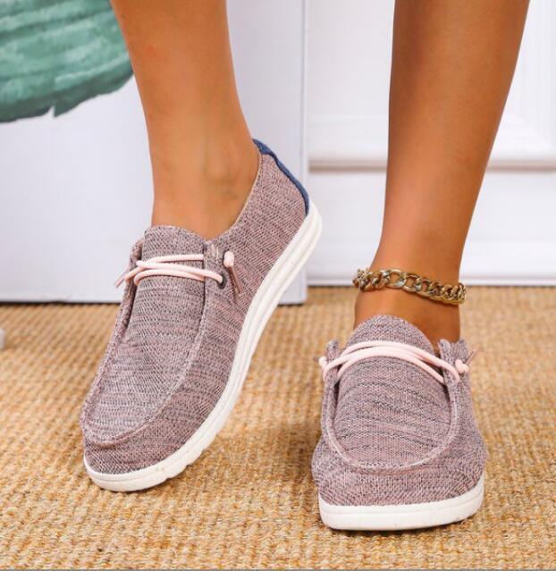 Women's casual slip-on shoes with knit fabric upper and white sole on carpeted floor