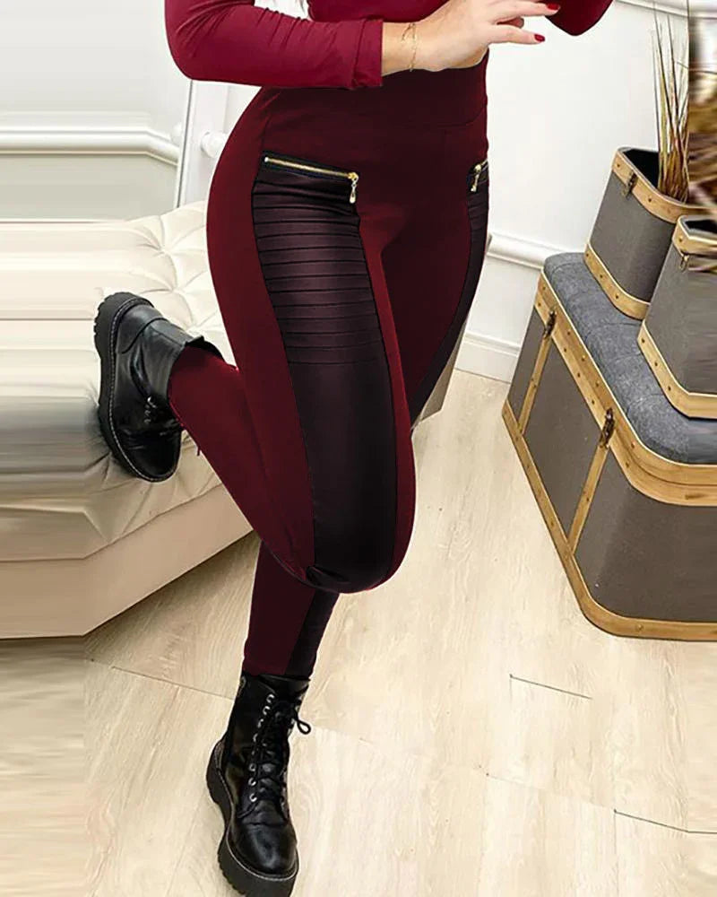 Woman wearing burgundy leggings with black textured panels and gold zipper accents, paired with black lace-up boots indoors