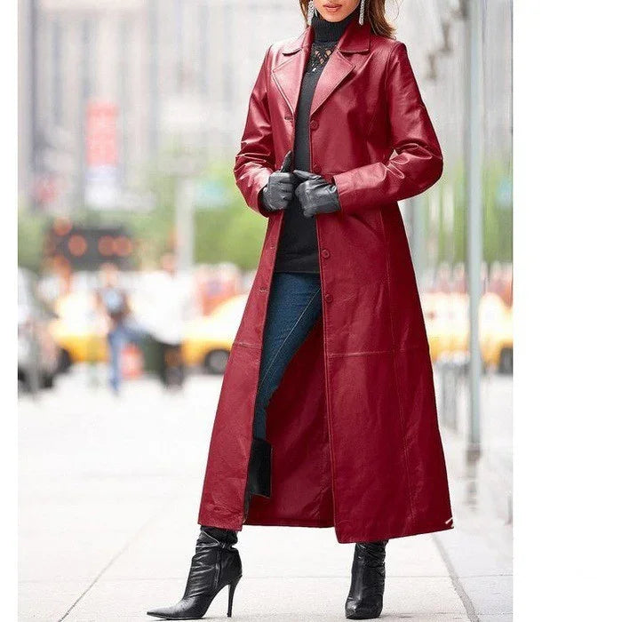 Woman wearing a long red leather coat, black gloves, black turtleneck, blue jeans, and black heeled boots in city street