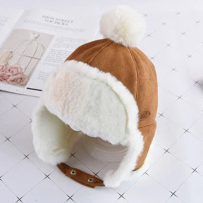Brown faux suede winter trapper hat with white faux fur lining and pom-pom on top