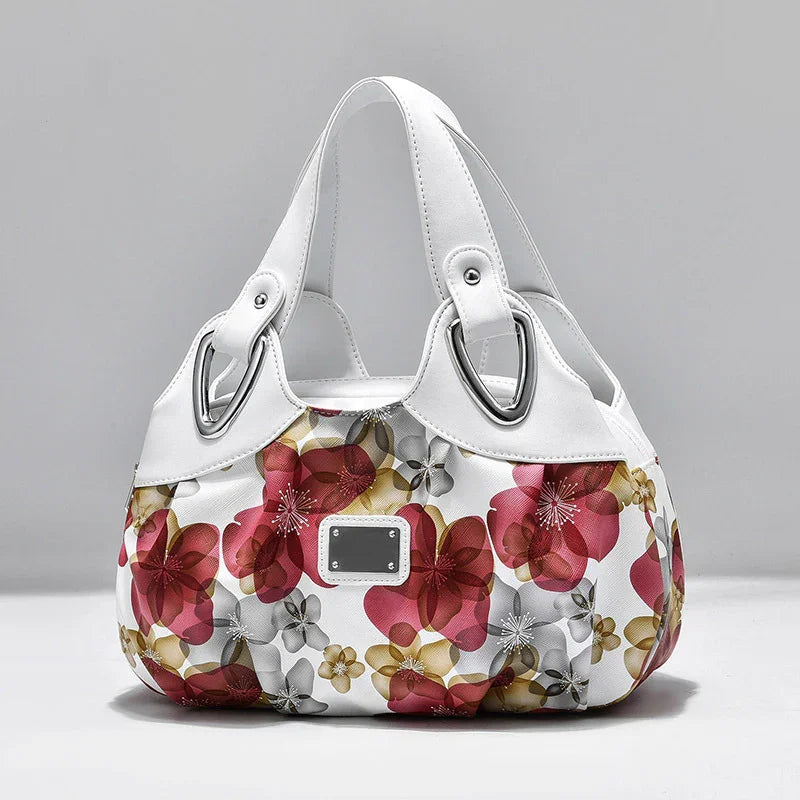 White handbag with large red, gold, and gray floral print and silver hardware details