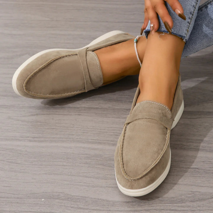 Women's beige suede casual loafers with white soles worn with shredded hem jeans