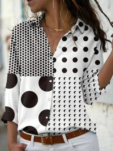 Woman wearing a stylish black and white polka dot and moon phase pattern button-up shirt with rolled sleeves