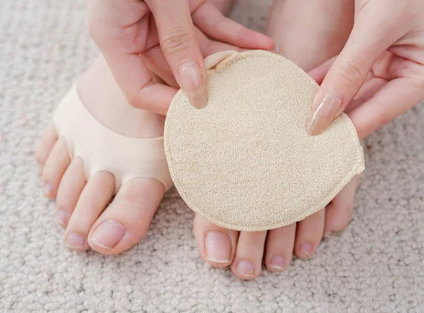 Person holding a beige toe pad for foot protection on carpeted floor