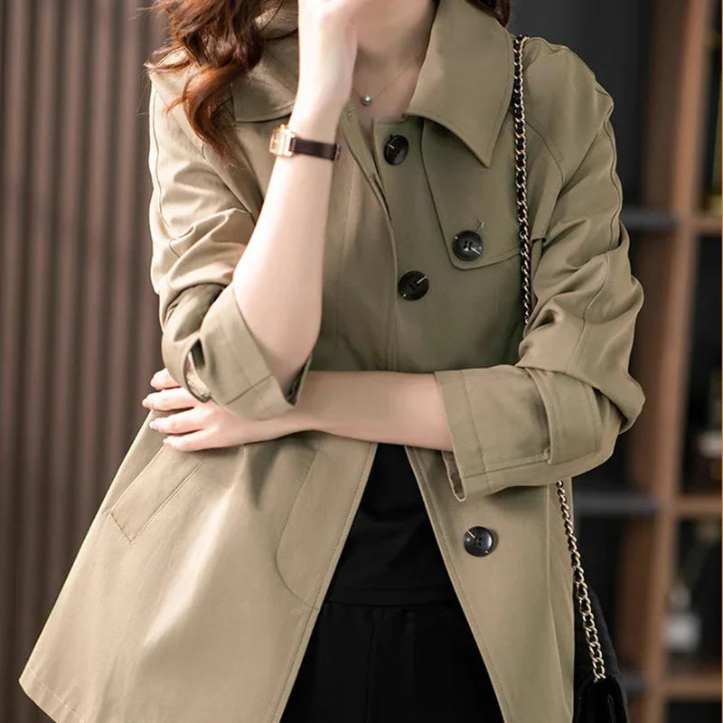 Woman wearing beige buttoned trench coat with rolled sleeves and black handbag strap
