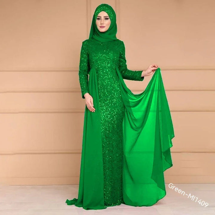 Woman in emerald green sequined evening gown with matching hijab holding flowing chiffon fabric