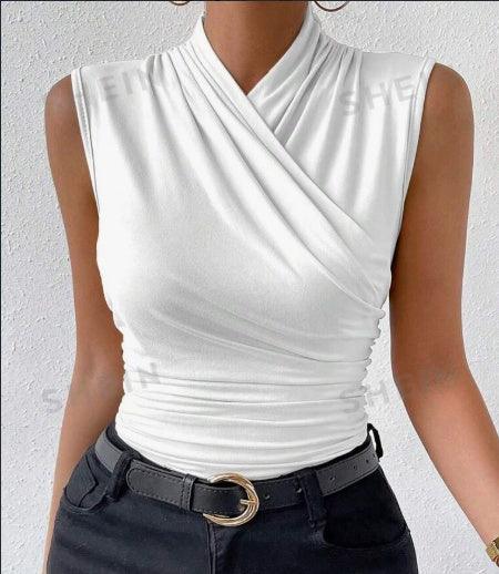 woman wearing sleeveless white wrap top paired with black pants and black belt with gold buckle