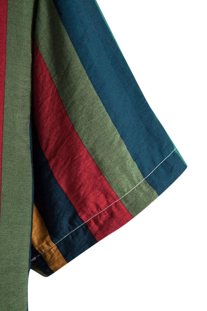 Colorful striped fabric close-up with blue, red, green, and mustard yellow vertical stripes and a white stitch