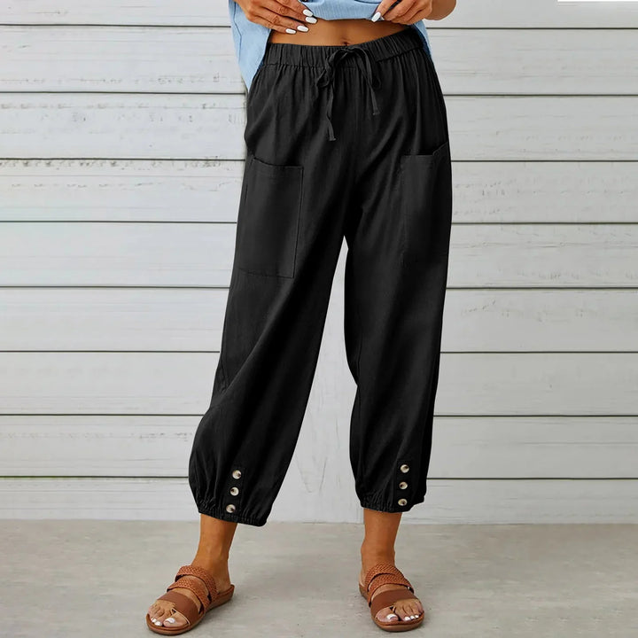 Black casual cropped pants with front pockets and button details, paired with brown sandals