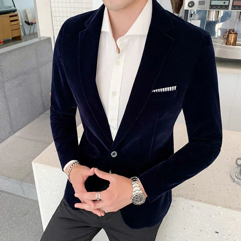 Man wearing black velvet blazer, white dress shirt, silver watch, and rings in modern kitchen