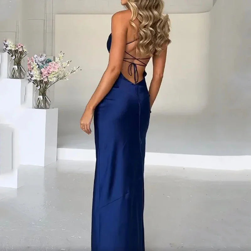 Woman in elegant navy blue backless evening gown with lace-up detail in minimal studio setting