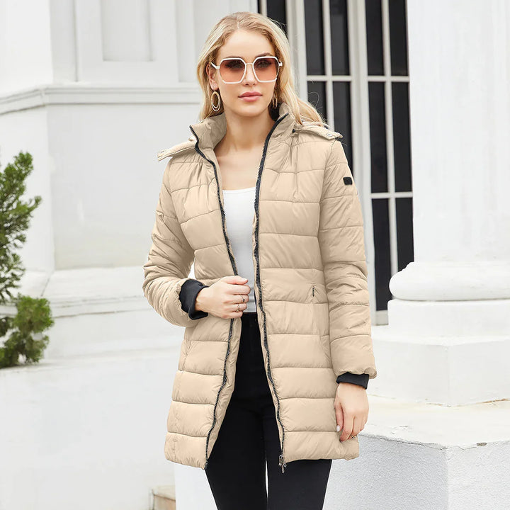 Woman wearing beige quilted long puffer jacket with sunglasses in urban outdoor setting