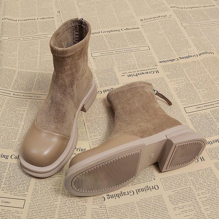 Pair of beige suede and rubber sole ankle boots on newspaper background