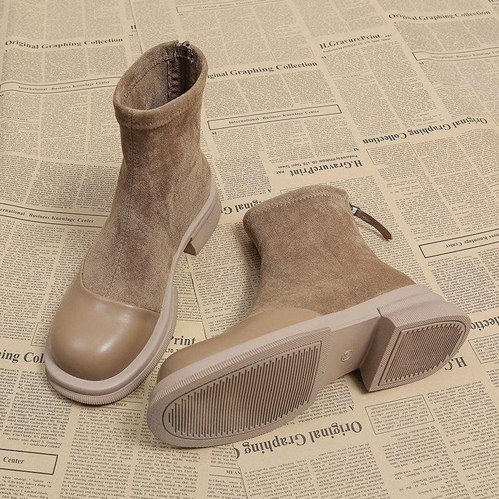 Pair of beige suede and rubber sole ankle boots on newspaper background