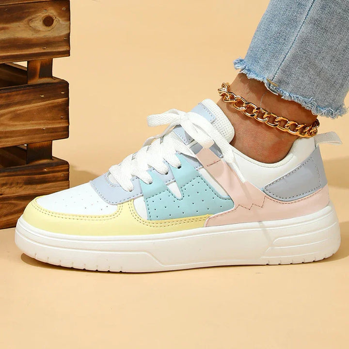 Colorful pastel casual sneakers with white laces worn with light blue jeans and gold chain anklet