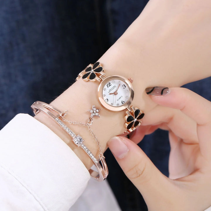 Rose gold quartz wristwatch with black flower design and rhinestone bracelet on wrist