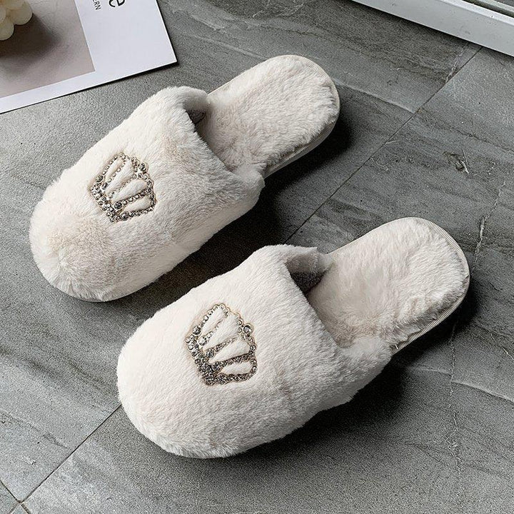 Soft white plush indoor slippers with jeweled crown decoration on gray tile floor