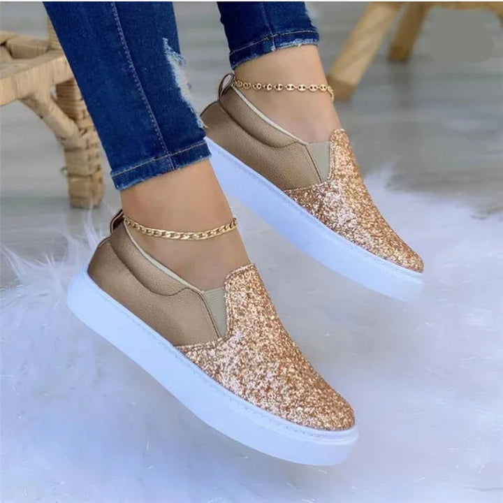 Gold glitter slip-on sneakers with white soles worn with blue jeans and gold ankle bracelets