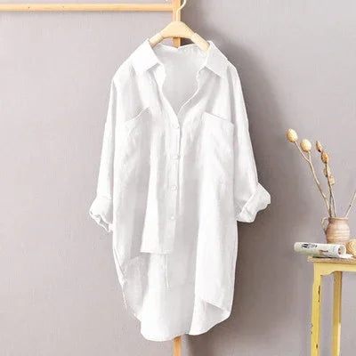 White casual button-up shirt with rolled sleeves hanging on wooden hanger against gray wall