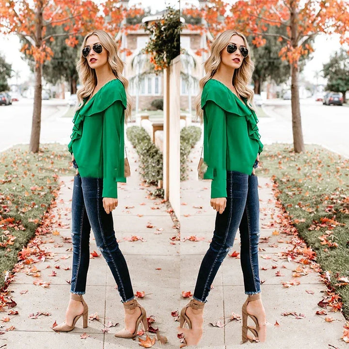 Fashionable woman wearing green ruffle blouse, dark skinny jeans, and nude heels walking outdoors in autumn